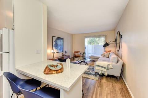 Kitchen with View of Living Room, Hardwood Inspired Floor, White Table and Blue Chairs